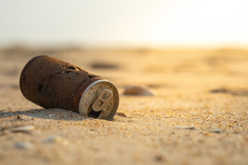 Old rusty can dropped on the sand beach.