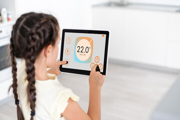 Shot of little girl using a domotic system with her digital tablet while standing at home.