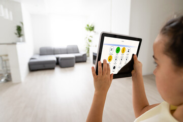 little girl using tablet with home remote control , living room in background, smart home