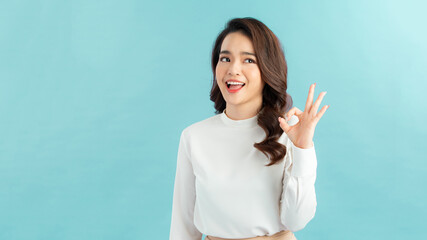 Young asian woman isolated on blue background showing ok sign with fingers