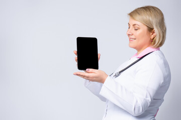 Doctor holding digital tablet computer mock up black screen consulting patient online video calling on gray background. Telemedicine video call consultation concept. Close up view