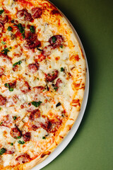 Top view pizza with mushrooms and tomatoes on a green-red background