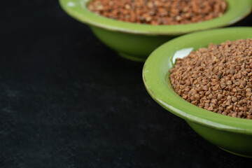 A green plate with uncooked dietic buckwheat