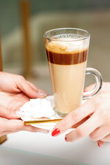Closeup of woman's hands taking the latte cup from hands of a barista in a coffee shop