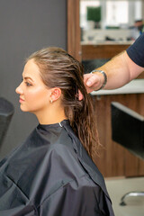 Naklejka premium Young woman with wet long hair receiving hairstyle in a hair salon