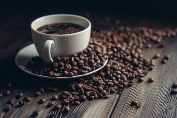 fragrant coffee beans on a wooden table and a cup with a hot drink on a saucer