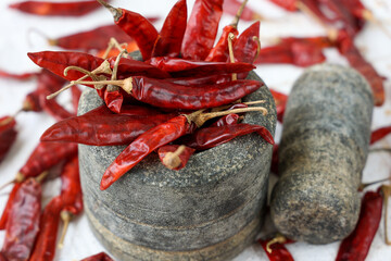 handmade powdering whole Indian spices Red chilly , chili powder use stone mortar Indian Kitchen Kerala India Sri Lanka. traditional curry masala , paprika , curry powder to make hot spicy curry