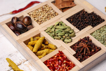 Indian spices for Indian cooking Masala hot spicy curry  whole spices turmeric, cardamom, black pepper in wooden spoon curry leaves paprika in Indian spice box Kerala India Sri Lanka.