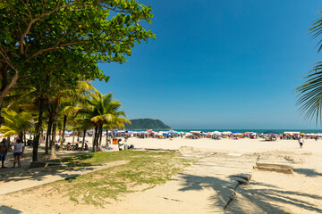 Beautiful sunny day at the beach. Tourists on crowded beach in the city Praia Grande on the coast of Sao Paulo, Brazil - obrazy, fototapety, plakaty