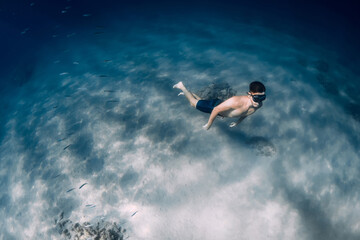 Fototapeta na wymiar Male free diver glides underwater in clear ocean in Hawaii