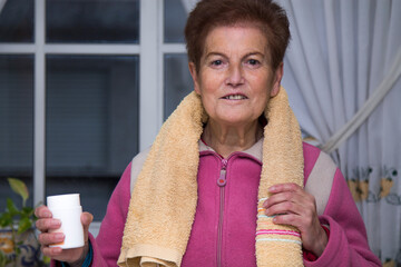 senior woman with bottle of vitamins or food supplements for sports. health and sport concept