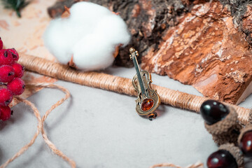 Decoration in the form of a violin of bronze and amber on a gray background close up