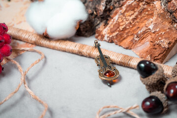 Decoration in the form of a violin of bronze and amber on a gray background