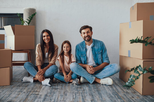 Young parents and their daughter posing happily in new house