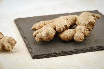 ginger roots on black slate plate. fabric tablecloth on table