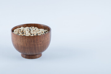 A small wooden bowl full of raw white peas