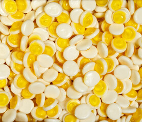 Candies in the shape of a circle with yellow filler for background. Top view.