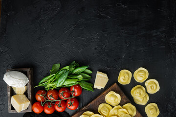Homemade Ravioli with mozzarella cheese and basil, on wooden cutting board, on black background, top view flat lay,  with copy space for text