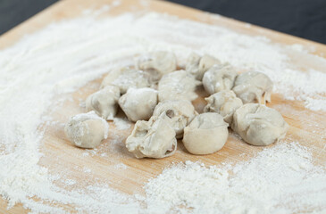Fototapeta na wymiar Raw dumplings with flour on a wooden board