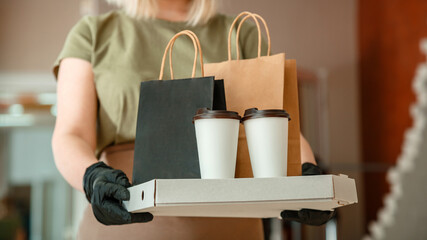 Waiter giving takeout meal while city covid 19 lockdown. Unrecognizable woman waiter in protective medical mask and gloves work with takeaway orders. Food Pizza coffee delivery. Long web banner