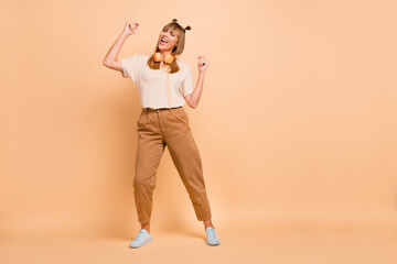 Fototapeta na wymiar Full length body size photo of overjoyed dancing singing girl wearing headphones isolated on pastel beige color background blank space