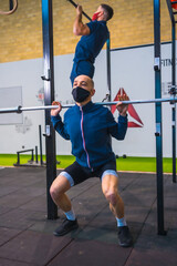 Obraz premium Two young people doing strength exercises in the gym in the coronavirus pandemic, a new normal. With protective face mask