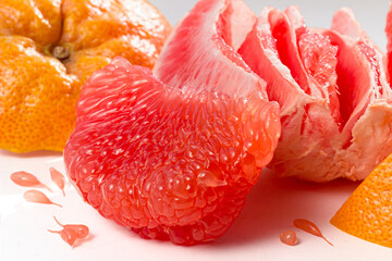 Fresh red grapefruit pulp and peel on white background close up. Peeled citrus fruit background.