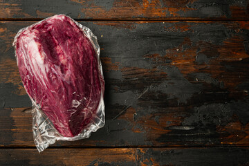 Marble beef in vacuum packed, on old dark  wooden table background, top view flat lay,  with copy...