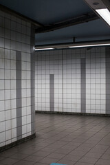 hallways without people of an industrial style underground subway with light tiles and lights and a tape barring the way