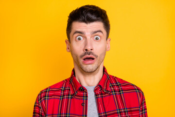 Photo of sad shocked young man wear red checkered shirt big eyes open mouth isolated yellow color background