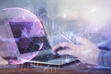 Double exposure of man's hands holding and using a digital device and forex graph drawing. Financial market concept.