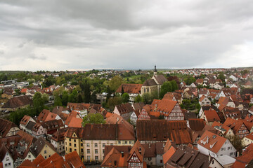 Obraz premium Aerial view of the city of Bad Wimpfen, Germany, with many tight red roofs and green trees between the houses on a cloudy day. There are some typical German timber-frame facades.