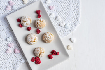 Obraz na płótnie Canvas baked low sugar vegan coconut crincle cookies bisquits on a romantic crochet white table cloth with freeze dried raspberries