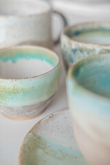 Turquoise handmade cups. Kitchen tea set on a white table. Minimalistic set of dishes
