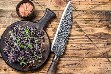 Radish microgreens, green leaves and purple stems. Wooden background. Top view. Copy space