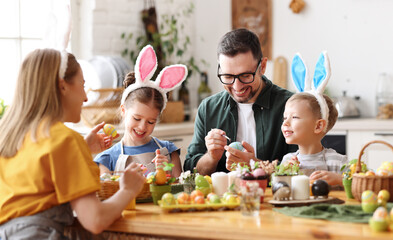 Happy family painting Easter eggs in light kitchen