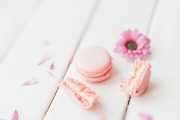 Beautiful flower and macaroon of pink color against a white background. One whole macaroon and another broken one. Gift to a loved one