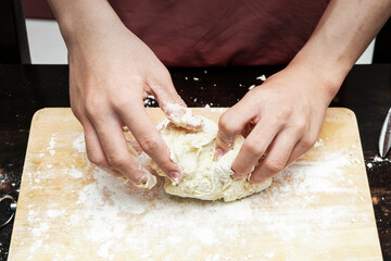 close up of hands kneading flour on a kneading board.