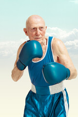 Senior man wearing sportwear boxing isolated on sky background. Caucasian male model in great shape...
