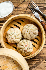 Asian steamed dumplings Manti in a bamboo steamer. Wooden background. Top view