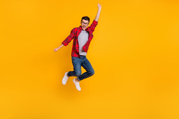 Fototapeta na wymiar Full size photo of young happy positive funky man in glasses jumping in victory isolated on yellow color background