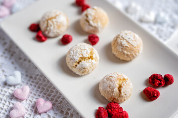 baked low sugar vegan coconut crincle cookies bisquits on a romantic crochet white  table cloth with freeze dried raspberries