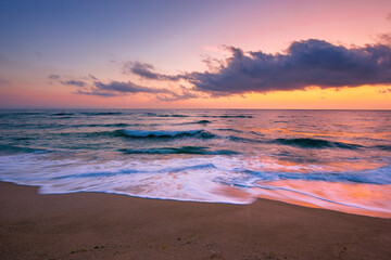sea beach with dramatic sky at sunrise. beautiful vacation background. waves rolling on the sand in morning light