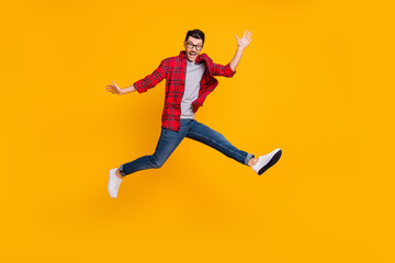 Fototapeta na wymiar Full length photo of funny young man wear checkered shirt eyewear jumping high isolated yellow color background