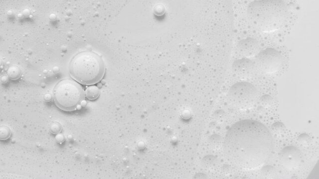 White acrylic paint bubbles abstract background 4k footage. Bubble is breaking. Liquid oil texture. Macro pattern art. Close-up cosmetic laboratory, science concept