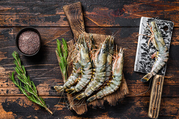 Fresh Raw black tiger prawns, shrimps on a cutting board.  Dark wooden background. Top view