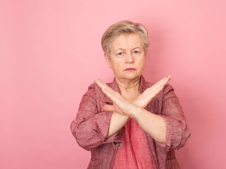 Senior aged woman rejection expression crossing arms and palms doing negative sign gesture with angry face.