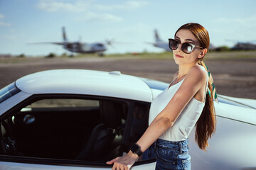 Beautiful girl in sunglasses on the background car and airplane 