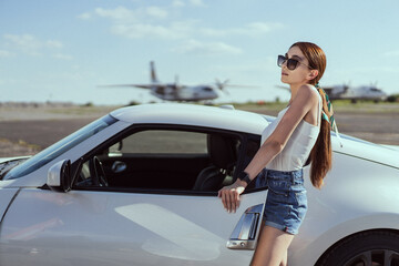Beautiful girl in sunglasses on the background car and airplane 
