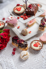 beautiful tasty romantic selection of pink chocolate love heart shape cakes for wedding, mothers day,  valentines day, spring flower biscuits tartlet and rose petals 
